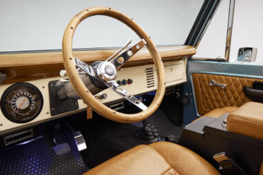 1976 Ford Bronco in Brittany Blue with whiskey diamond stitch leather interior and wood grain steering wheel