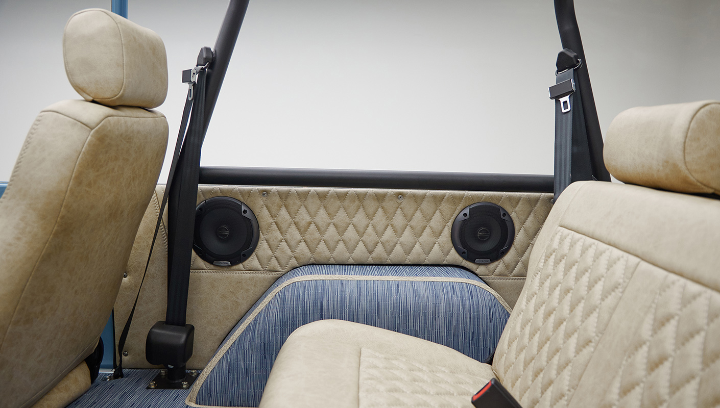 A 1976 Classic Ford Bronco is Frozen Blue over White Rock leather rear seat speakers