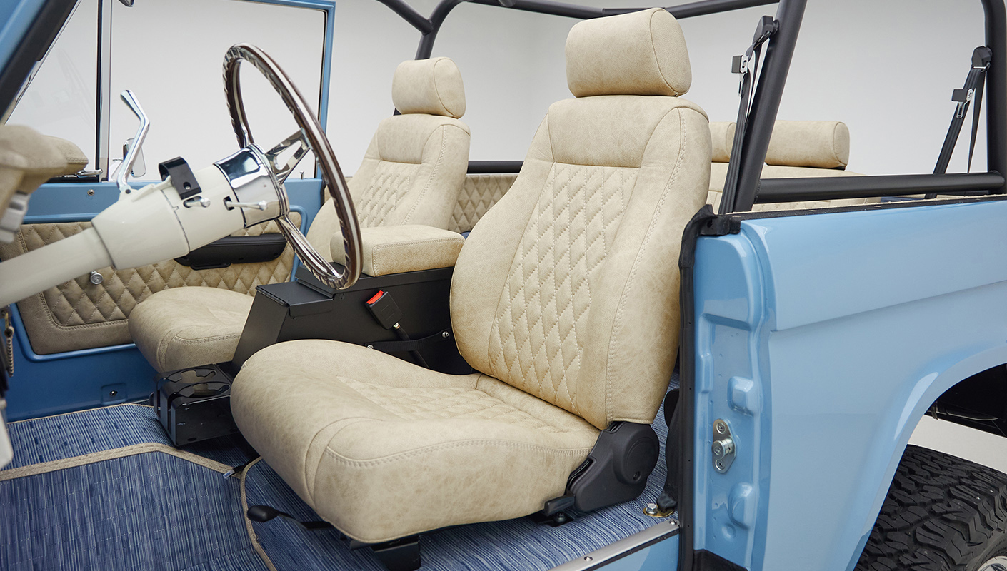 A 1976 Classic Ford Bronco is Frozen Blue over White Rock leather driver interior